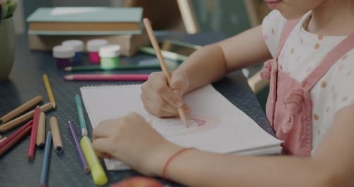 Child Drawing with Colored Pencils on a Table