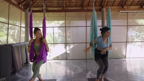 Feet of Unrecognizable Yoga Instructor Hanging on Green Hammock in Studio