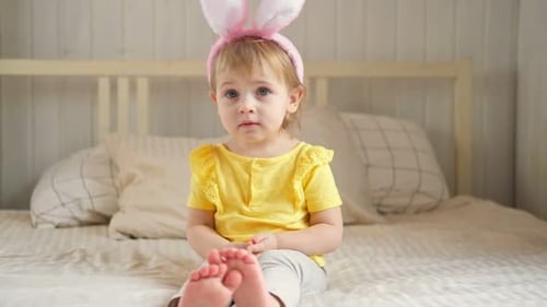 Adorable Child Wearing Bunny Ears on Bed