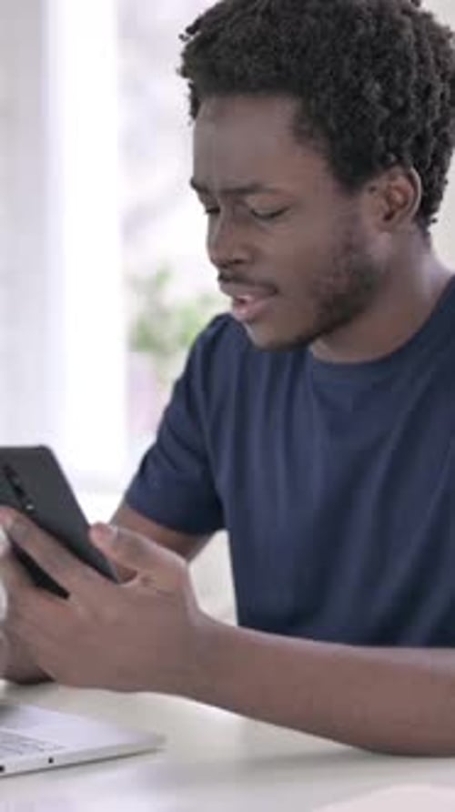Young African Man using Smartphone in Modern Office, vertical video