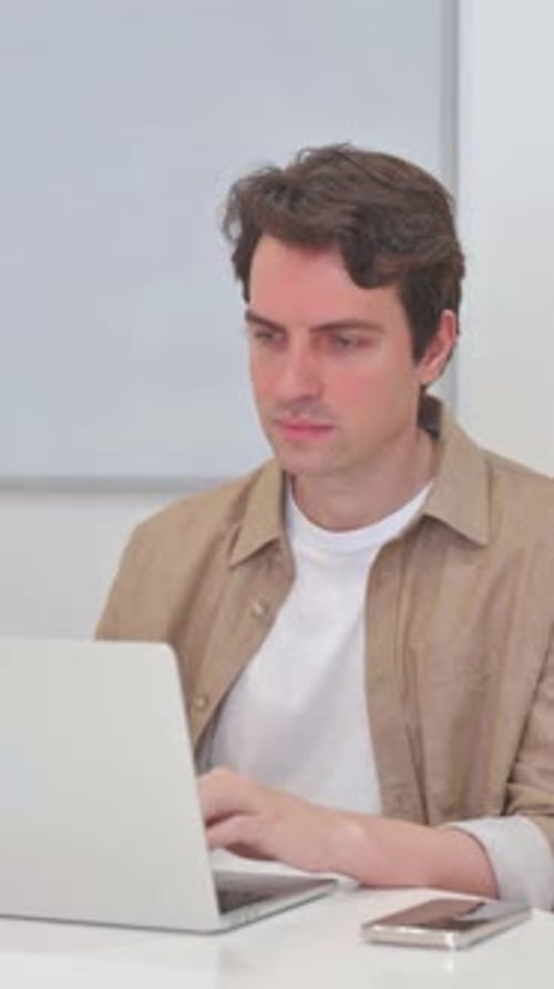Man Smiling and Typing on a Laptop