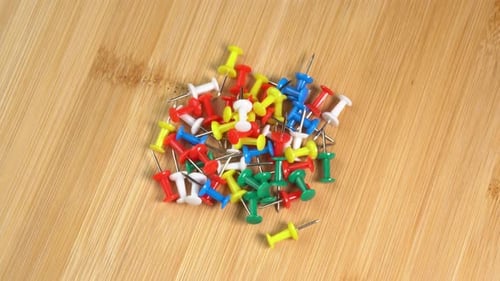 Colorful push pins rotating on the desk. Drawing pins for marking on the map of the Earth or city