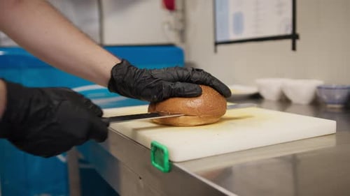 Chef Slicing In Half A Bun To Start The Preparation Of The Burger