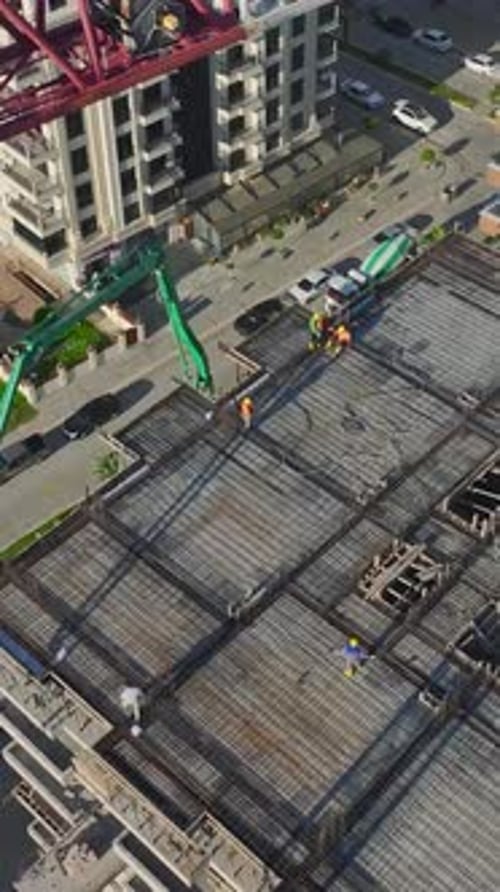 Vídeo vertical de ingenieros supervisando una grúa levantando materiales mientras los trabajadores construyen paredes y