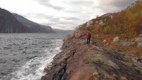 Drone shot of a hiker walking close to the Norwegian fjord