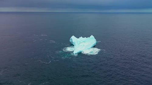 Images prises par un drone montrant un iceberg dans une houle agitée en haute mer avec des calottes blanches au large des côtes de Terre-Neuve