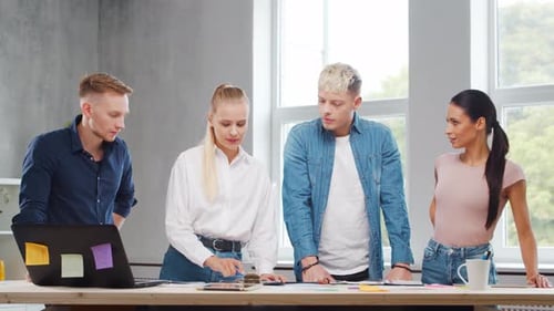 Team of Young Startupers is Working at the Table in the Office Discussing the Strategy and