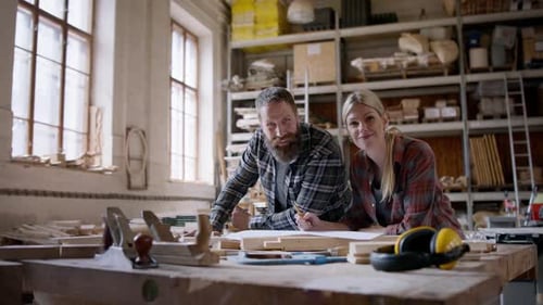 Carpenters discussing design and looking at camera in workshop small business concept