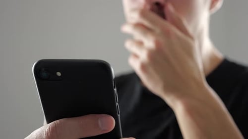 Young Adult Using Smartphone, Covering Mouth in Shock