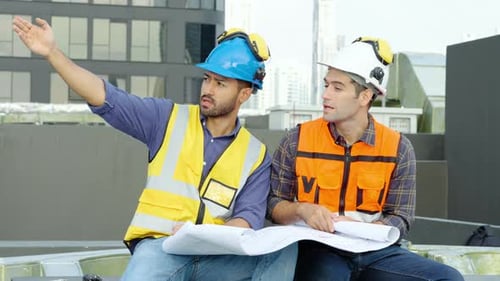 Zwei Bauingenieure sitzen zusammen und überprüfen gemeinsam Informationen aus dem Bauplan, Projektmanager