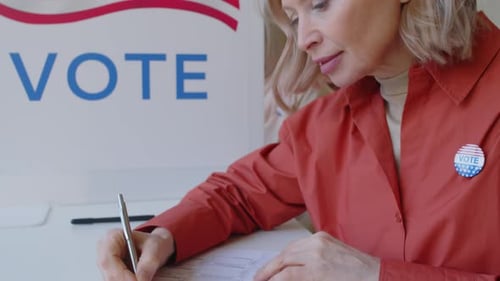 Mature Woman Marking Paper Ballot at Voting Booth