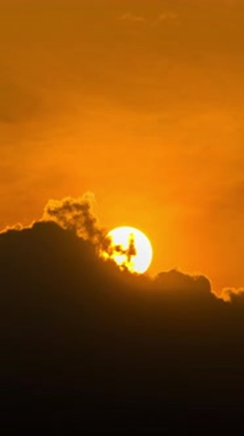 Sun Rising Through Clouds in Orange Sky