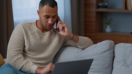 Man talking on a smartphone while using laptop