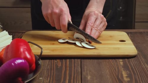 Slicing Mushrooms on a Wooden Board in Kitchen