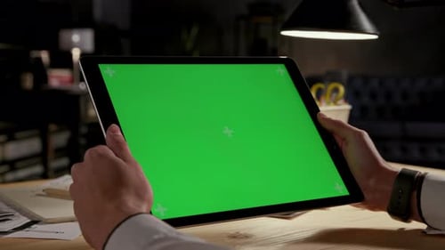 Businessman holding tablet computer with green screen chroma key mockup in office