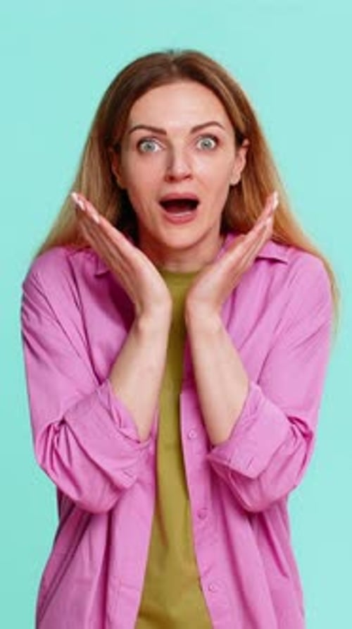 Woman with shocked expression against blue backdrop