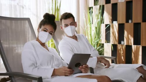 Young couple enjoying relaxing spa day using tablet at luxury hotel