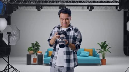 Asian Photographer Taking Pictures Then Looking At Them In The Camera In The Studio
