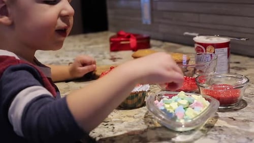 Kleiner Junge legt Bonbonherz auf den Cupcake zum Valentinstag