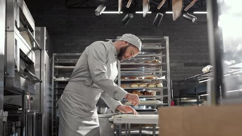 Caucasian Goodlooking Man Working in Bakery and Cutting Dough for Cookies on Workday Morning Cooking