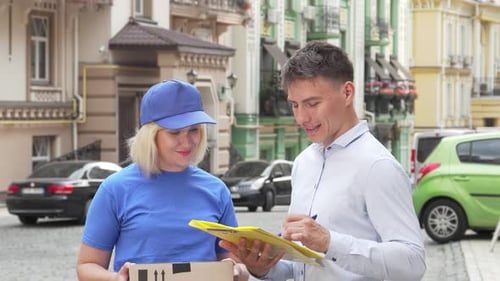 Female Courier Joyfully Delivering a Package to a Young Man on a Vibrant City Street