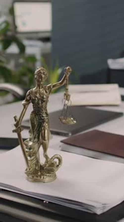 Vertical of Lady Justice Statuette on Pile of Documents on Office Table