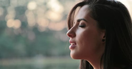 Young woman with eyes closed taking a deep breath outside at the park