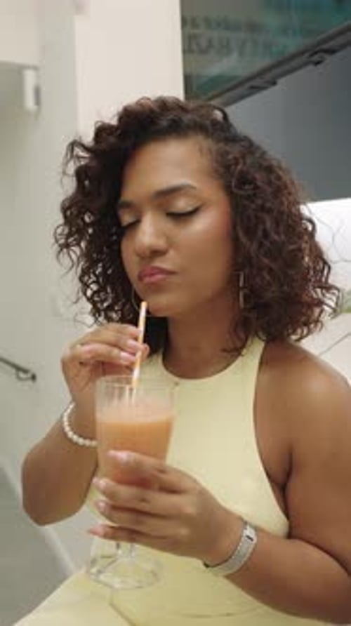 Woman Sips Refreshing Drink Through Straw in Bright Setting