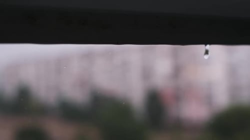 Raindrops Falling from Edge with City Background