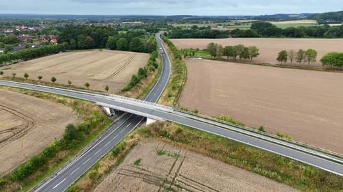Truck on interstate highway between wheat fields in suburbia of city. Aerial flyover shot. Bridge le