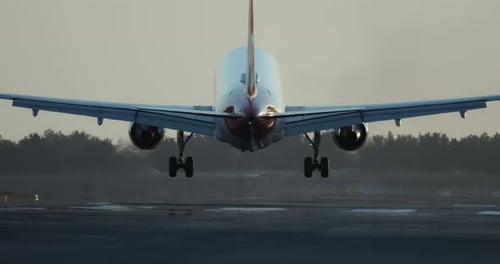 Slow Motion Video of an Airliner Landing on an Airport Runway at Sunset