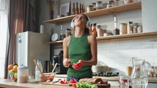 Woman Dancing and Chopping Vegetables in Kitchen