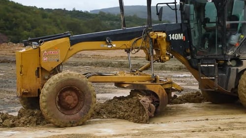Road Grader Vehicle Moving Dirt on Cloudy Day
