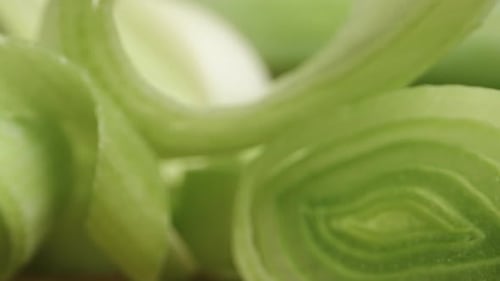 Pieces of sliced green leek on a black background. Dolly slider extreme close-up.