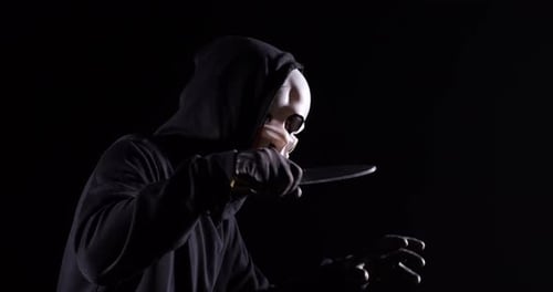 Side View Of Scary Man In Halloween Mask Holding A Knife While Running On The Black Background