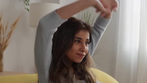Woman Stretching Arms at Home on Couch