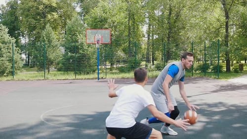 Hübscher Sportler spielt Basketball mit zwei Freunden, die den Ball dribbeln