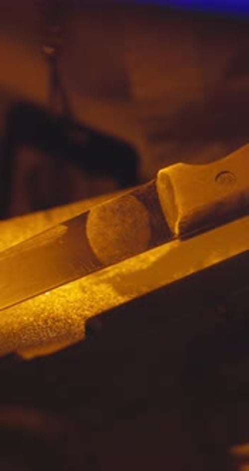 Close-up of a reflective, silvery blade in darkness