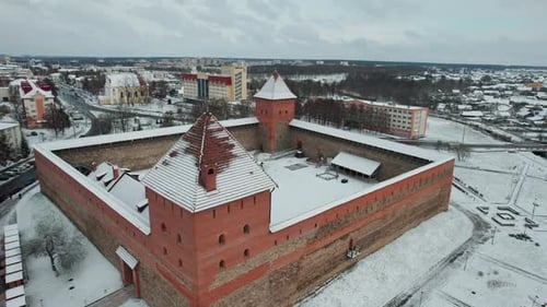 Aerial View of a Medieval Castle with Two Red Brick Towers and City Panorama on a Winter Day