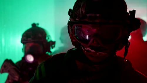 Figures in Tactical Gear Stand in Colorful Lit Room