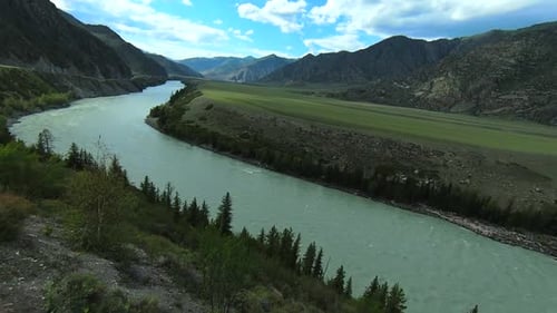 Drone flying over turquoise river flows in intermountains.