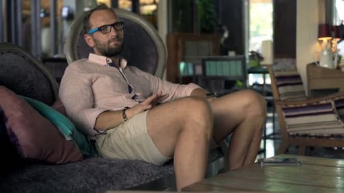 Impatient man checks watch and phone awaiting late date at trendy cafe