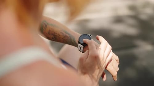 Redhead Female Athlete Syncs Smart Watch to Monitor Workout Stats in Tropical Outdoor Gym Fitness