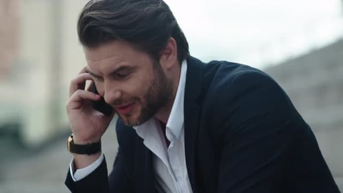 Happy businessman celebrating victory talking on smartphone in city street outdoors