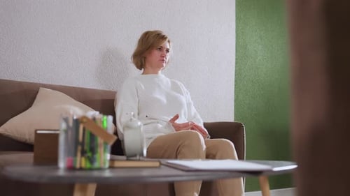 Invité conscient assis sur un canapé démontrant avec les mains