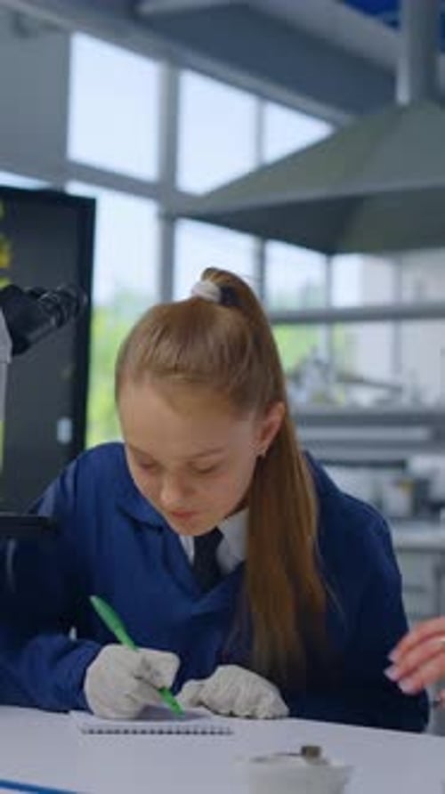 Young Girl Student Works with Microscope in Science Lab