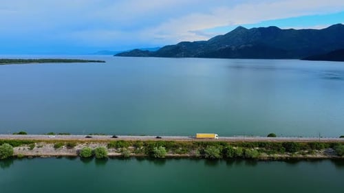 Aerial view, aerial drone footage: long haul semi cargo truck driving on a bridge between two lakes
