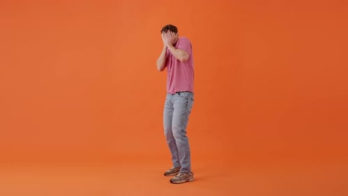 Scared Male Covering Face By Hands and Peeking Out Indoor