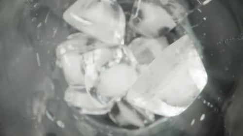 Ice cubes falling into a glass, Top view on a black background, slow motion, macro Slider