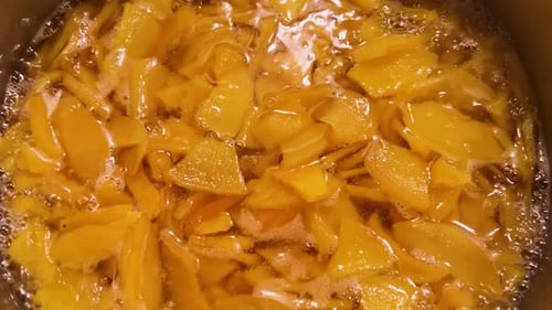 La confiture de coings est en train de bouillir dans une grande casserole. Remuer la confiture avec une spatule en silicone.